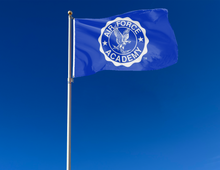 Load image into Gallery viewer, Blue 3x5 foot Air Force Academy flag with two metal grommets attached to a flagpole as it sways in the wind
