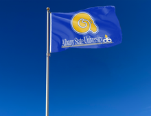 Load image into Gallery viewer, Blue 3x5 foot Albany State University Flag with Two Metal Grommets attached to a flagpole as it waves in the wind
