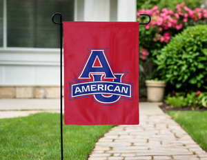 Red 13x18 inch long American University Garden Flag hanging on a black Garden flag stand in front of a yard