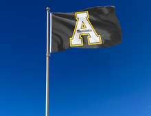 Load image into Gallery viewer, Black 3x5 foot Appalachian State University Flag with A Mountaineers logo and Two Metal grommets attached to a flagpole waving in the wind
