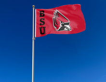 Load image into Gallery viewer, Red 3x5 foot wide Ball State University flag with BSU Logo and two metal grommets attached to flagpole waving in the wind
