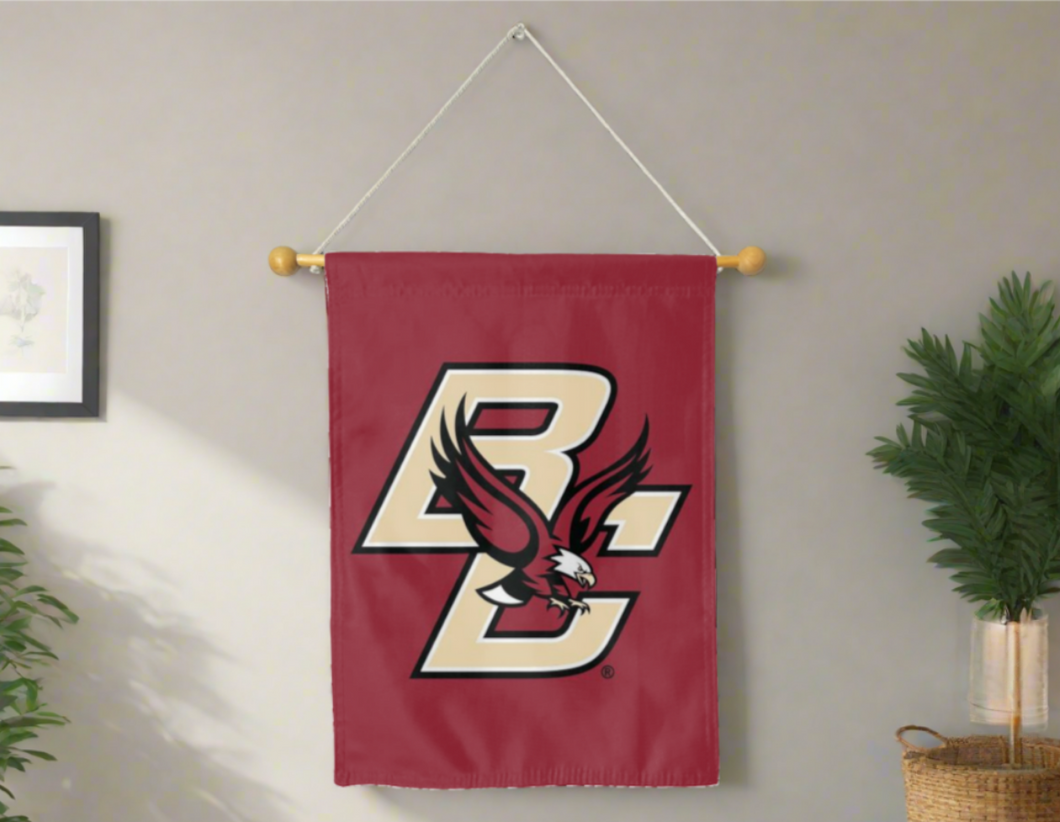 30x40 inch long Boston College House Flag hung on a banner pole in front of a grey wall with one plant on the left side and another one on the right side