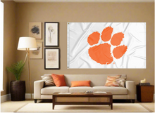 Load image into Gallery viewer, white 3x5 foot wide Clemson University Flag with two metal grommets covering the tan wall inside of a well organized room with couch pillows and light
